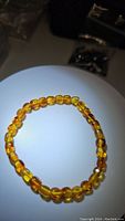 Front view of honey maple Baltic amber bead stretchy bracelet placed on a white surface with some background items visible.