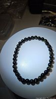 Top-down view of natural gold sheen obsidian bead bracelet laid flat showing full loop and bead color.