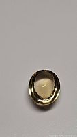 Oval cabochon cut natural golden citrine gemstone with golden color and some internal features.