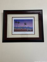 Framed printed art showing the full framed piece with dark wood frame and matting around the print.
