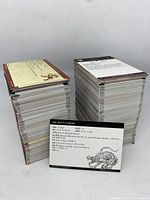 Two large stacks of Dungeon and Dragons miniatures stat cards with one card displayed front-facing showing RPG character statistics and illustration.