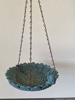 Photo showing hanging outdoor bird feeder/water dish with decorative petal rim, attached chains and bird motif.