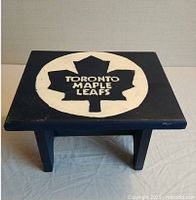 Top view of the small wooden step stool showing hand painted Toronto Maple Leafs logo.