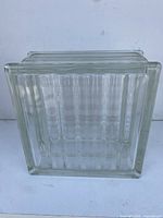 Front view of the square glass block showing the vertical ridges and wave patterns inside.