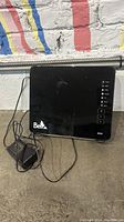 Front view of Bell branded black router with status lights and power adapter cable visible.
