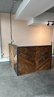 Full view of front and side of desk showing chevron-pattern reclaimed wood panels and steel edging