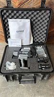 Gray and black EMist EPIX360 sprayer with two rechargeable batteries, charging cable, plastic nozzles, manual, all in foam-padded black hard case.