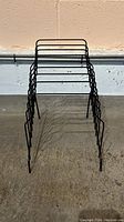 Black metal office file holder standing upright showing the frame and slots for files