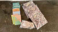 Overview of the lot showing 4 pajama sets, 1 pair slippers, notebooks and coloring books.