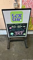 Front view of the sidewalk display sign showing a colorful insert for a closing sale promotion at a store.