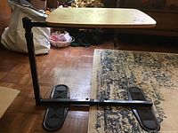 Metal base of the adjustable table showing the sliding and adjustable mechanism with two flat oval feet on the floor.