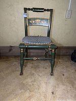 Full front view of painted wooden chair with rush seat needing repair, placed against basement wall.
