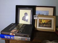 Books and framed prints arranged on wooden surface, showing two books and three framed historical prints related to the Civil War