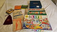 Wide photo showing entire lot including boxed The Game of Life, Cap Travel Game, Travel Games box, Bridal Shower games, playing cards.