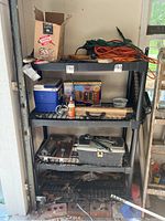 Photo of black metal shelving unit with various items including extension cords, tools, cooler, and boxes in garage