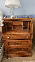 Front view of the wooden roll top desk with drawers and compartments visible inside the open roll top.