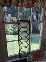 Stained glass art pieces displayed on a window sill showing sunlight through glass with nature background