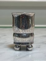 Front view of cup showing hammered finish and ball feet