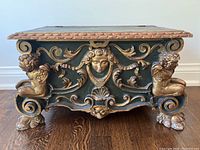 Front view of carved wooden storage bench showing scrollwork and cherub putti