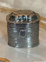 Front view showing embossed floral and geometric bands with a heart-shaped cartouche on the body.