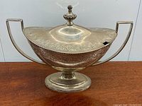 Front view of lidded sterling silver sugar bowl showing dual handles and decorative lid with urn finial.