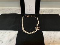 Full view of pearl necklace laid in pouch with Chanel box