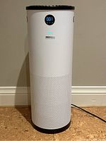 Front view of white cylindrical air purifier showing LED display and perforated intake