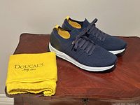 Pair of navy blue knit sneakers with lace-up detail and yellow dust bag