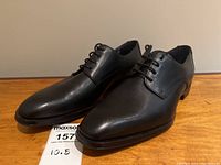 Pair of shoes three-quarter front view on wooden surface with MaxSold tag showing size