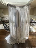 Front view of all eight panels hung on a rod at an indoor balcony railing