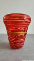 Front and side view of the red art glass vase showing overall shape and yellow ribbon accents