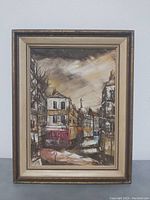 Full view of framed oil painting depicting a street scene with buildings and trees.