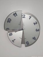 Front view of the modernist segmented wall clock showing the three divided sections with clear numbers and minute markers, environmental minor wear visible.