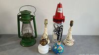 Full view of all six items including the large green lantern, Crayola lamp, two fabric-wrapped lamps, and two small oil lamps