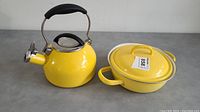 Photo showing the yellow Chantal kettle and matching yellow pot with lid side by side on a grey surface.