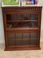 Front view of the dark wood barristers bookcase showing the two glass pane doors with eight panes each and brass knobs.