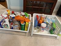 Two plastic laundry baskets filled with cleaning supplies arranged on carpet