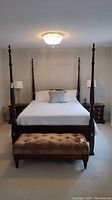 Full front and side view of king size four post bed with mattress and tufted bench at foot.
