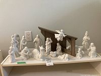 Full view of entire nativity set arranged on table, showing all porcelain figures and wooden stable.