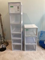 Front view showing two plastic organizers of different heights, one with five drawers and the other with three drawers, all translucent with white frames.