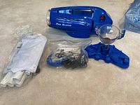 Main image showing Pool Blaster Millennium pool cleaner and included accessories including pipes, funnel and manual.