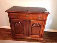 Front view of the Stanley Furniture server cabinet showing dark polished wood finish, drawer with brass handles, and two front doors with carved details.