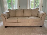 Front view of beige fabric sofa showing three seat cushions and rolled arms