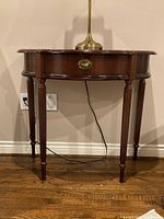 Front view of the half moon hall table showing the curved front, drawer, and fluted legs.