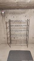 Full view of metal wine rack against concrete wall in basement.
