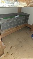 Steel storage chest with 9 labeled drawers under a workbench, showing condition and overall structure.