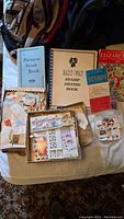 Photo showing multiple stamp stock and drying books including Paragon and Easy-Way brands, loose stamps in envelopes and boxes, and collectible coin packaging.