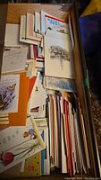 Drawer filled with stacked greeting cards, showing various card designs including floral and illustrated themes