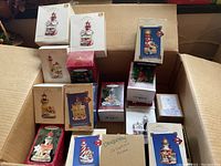 Overview of box full of Hallmark Keepsake lighthouse Christmas ornaments in original boxes.