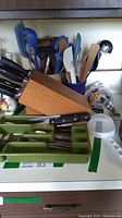 Knife block with Henckels knives and green tray with cutlery on kitchen counter, showing items included in lot